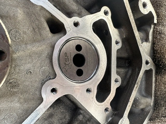 Close-up of a CNC camshaft retainer plate fitted to an engine block.