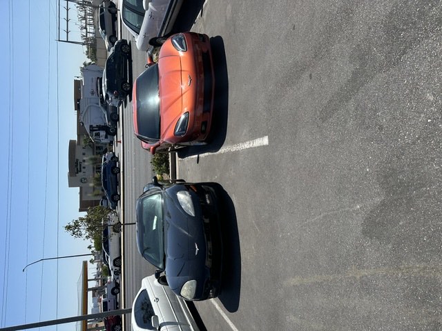 Two Chevrolet Corvettes, one black and one orange, parked at the shop.