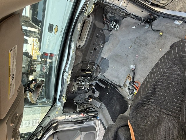 A vehicle interior stripped with the dashboard removed, seats covered to protect them.