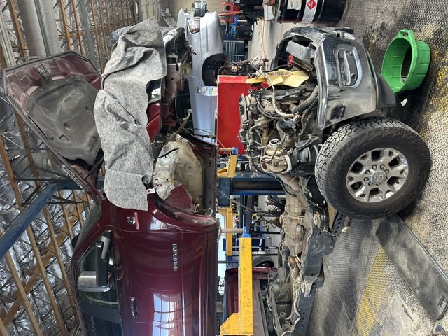 A Ram pickup with its cab lifted clear of the frame, exposing the engine and transmission for major drivetrain work.