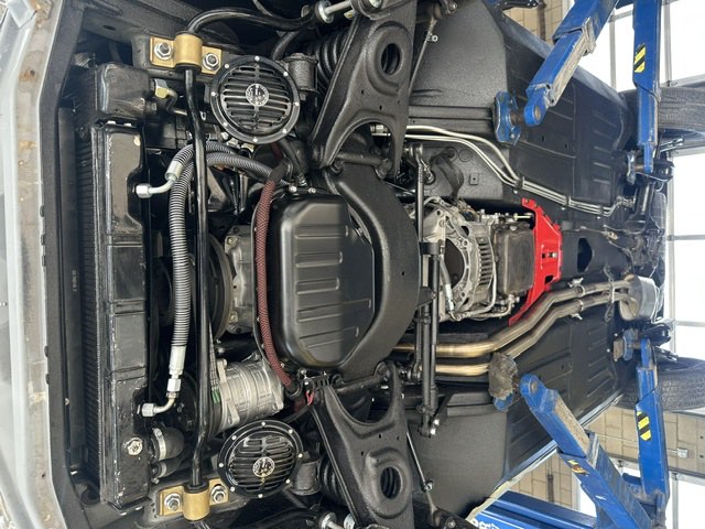 The underside of a vehicle raised on the lift, showing suspension, driveline and exhaust.
