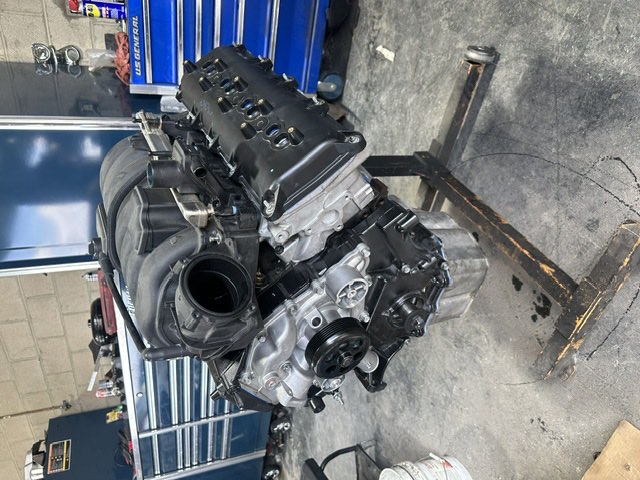 A modern V8 engine mounted on an engine stand in the workshop.